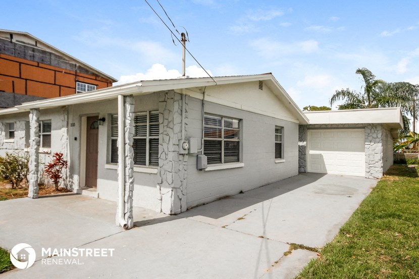 a small white house with a garage and a driveway