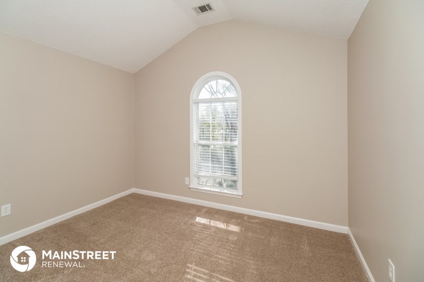 the master bedroom has a large window and carpeted flooring