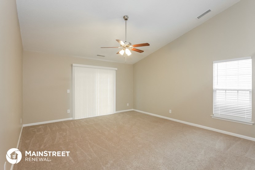 the spacious living room with carpeting and a ceiling fan