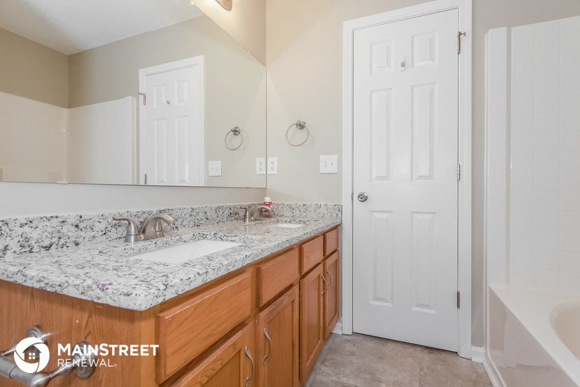 a bathroom with marble countertops and wooden cabinets and a white door