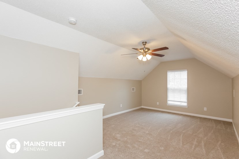 the spacious upstairs bedroom with ceiling fan and carpeting