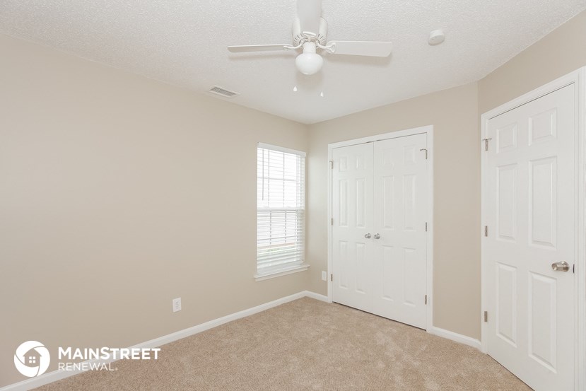 a bedroom with two closets and a ceiling fan