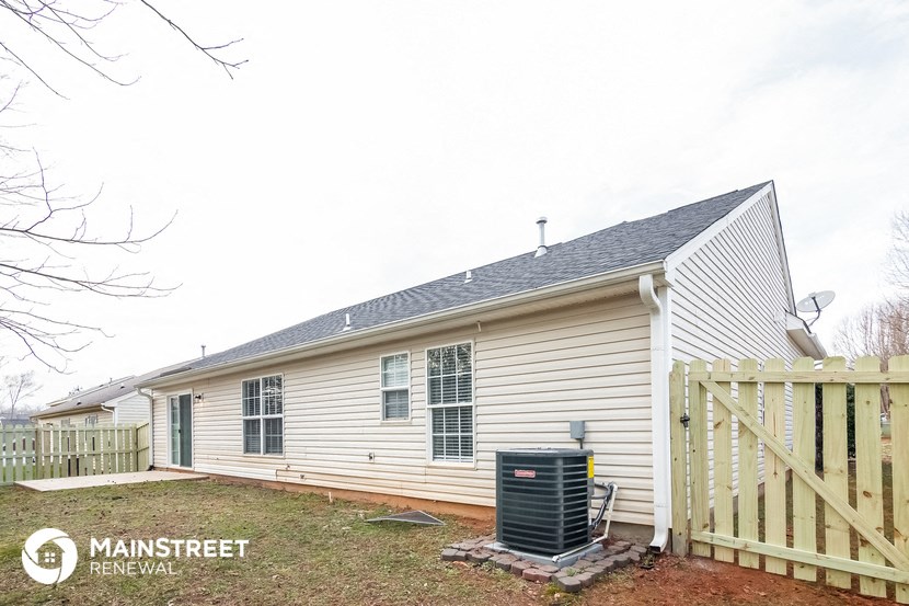 the back of a white house with a wooden fence and a heater