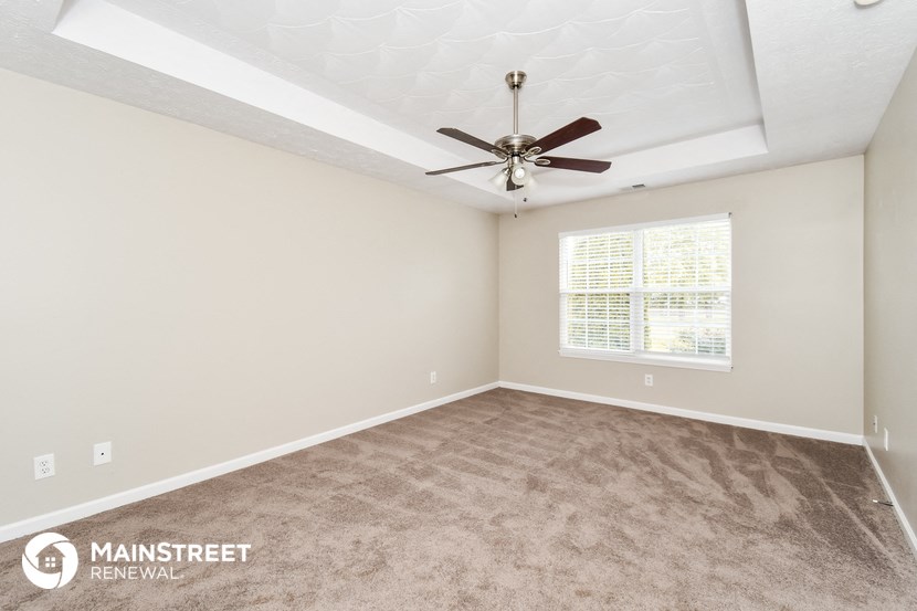 the spacious living room with carpeting and a ceiling fan