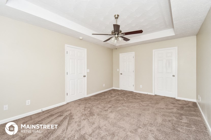 the living room of a new home with carpet and a ceiling fan