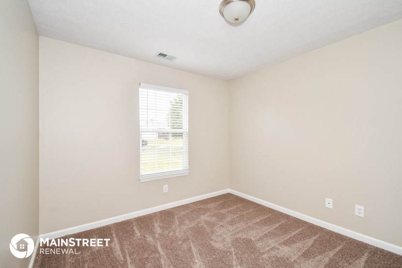 an empty room with a window and carpeted flooring