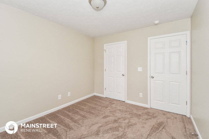 a bedroom with two doors and a carpeted floor