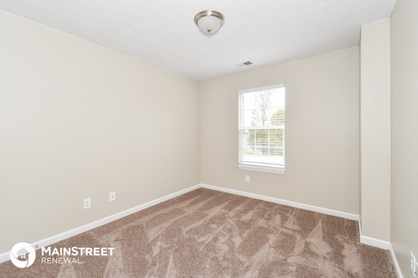 a bedroom with carpeted flooring and a window
