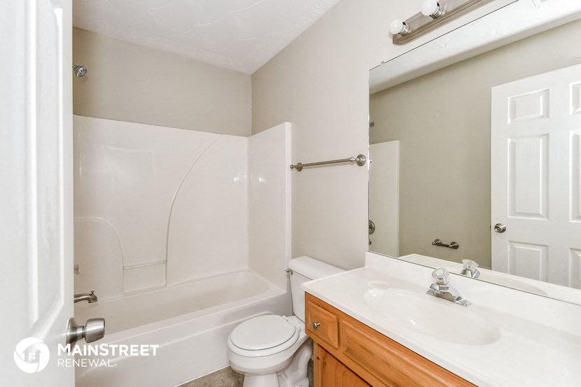a bathroom with a toilet sink and mirror and a tub