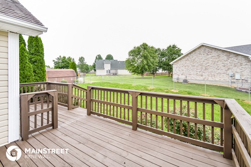a deck with a view of a yard and a house
