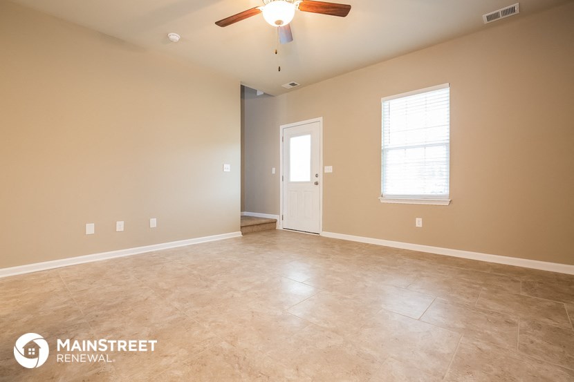 the spacious living room with tile flooring and a ceiling fan