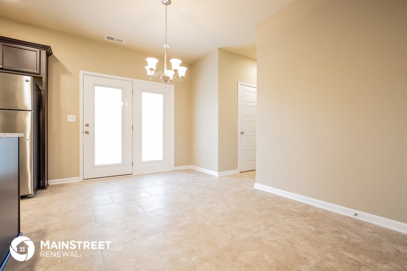 an empty kitchen and living room with a stainless steel refrigerator