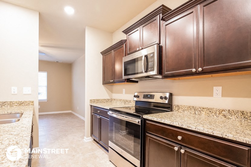 a kitchen with brown cabinets and black appliances and granite counter tops