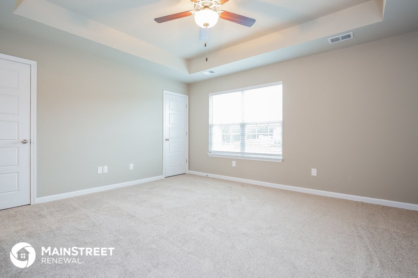 the master bedroom with carpeted flooring and a ceiling fan