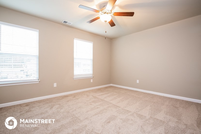 the spacious living room with carpeting and a ceiling fan