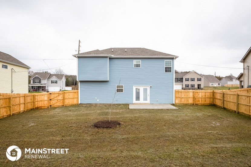 the backyard of a blue house with a wooden fence