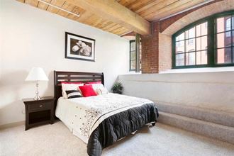 a bedroom with a bed and a brick wall