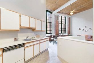 an empty kitchen with white cabinets and a large window