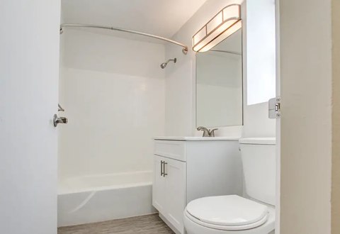 A white bathroom with a toilet, sink, and bathtub.