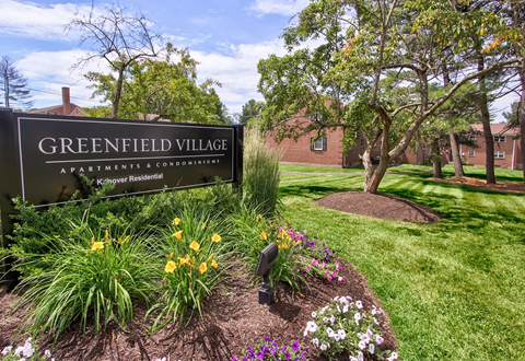 A sign that says Greenfield Village stands in front of a building.