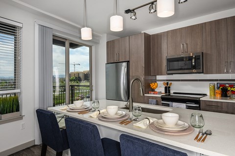 A modern kitchen with a dining table set for two.