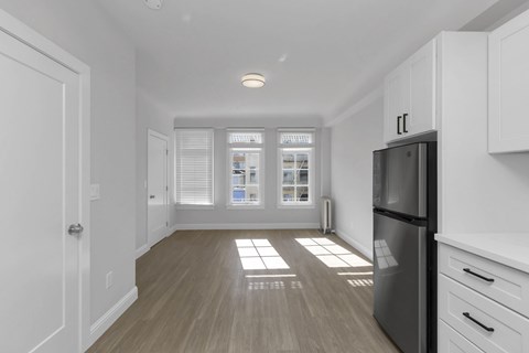 A kitchen with a black fridge and white cabinets.