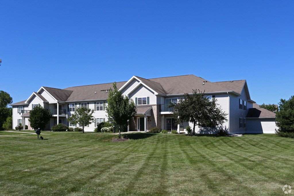 a large house on a green lawn with a blue sky