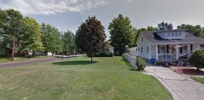 a white house with a porch and a yard and trees