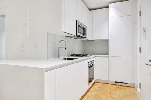 a white kitchen with white cabinets and a sink