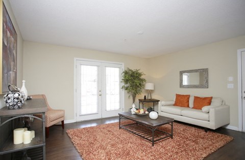 A living room with a white couch and a brown rug.