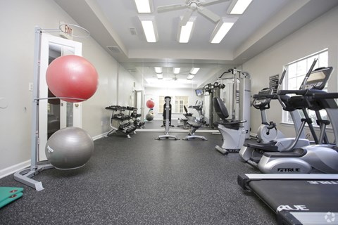A gym with a variety of equipment including treadmills, weights, and exercise balls.
