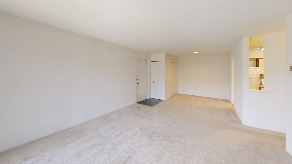 the living room and dining room of an empty home with white walls and flooring