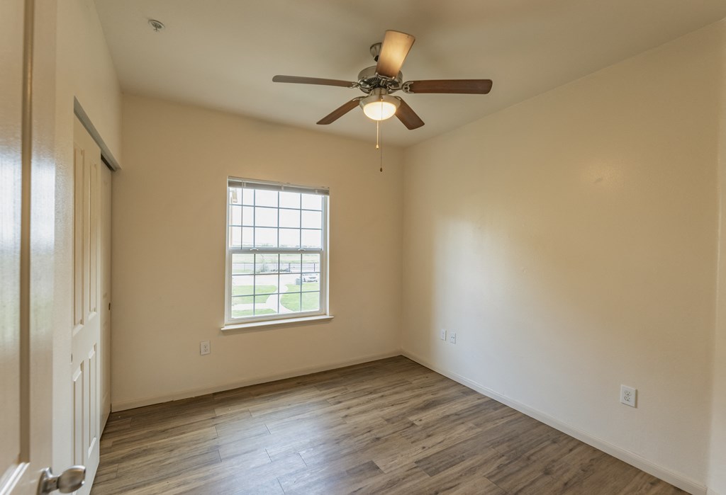 an empty living room with a ceiling fan and a window