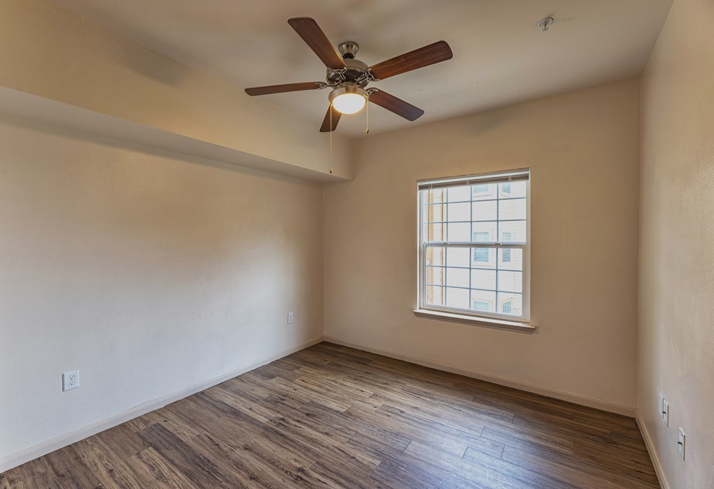 an empty living room with a ceiling fan and a window
