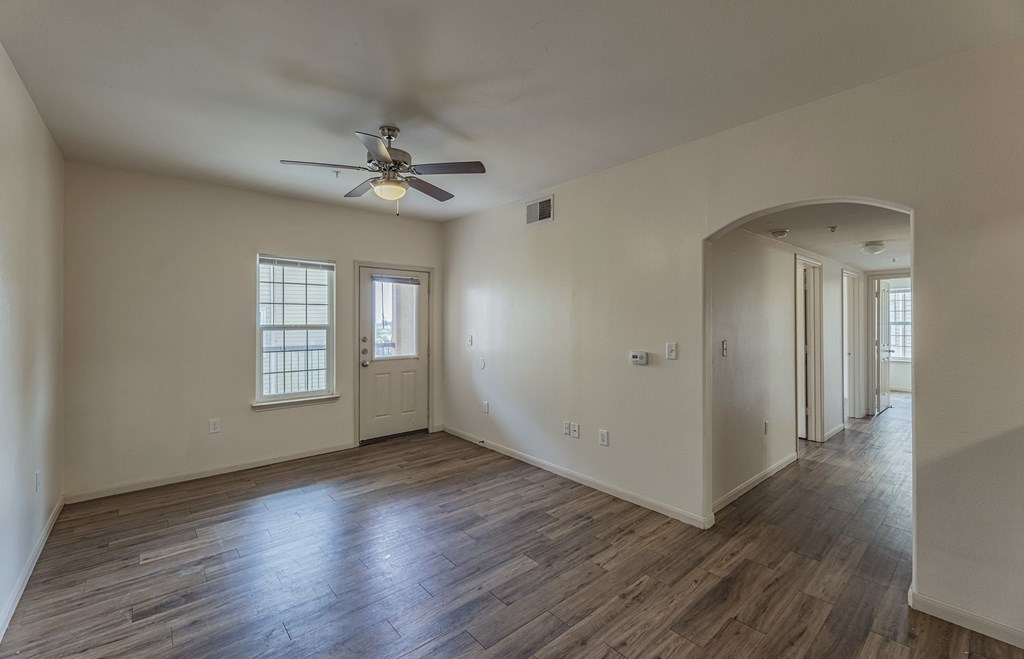 an empty living room with white walls and a ceiling fan