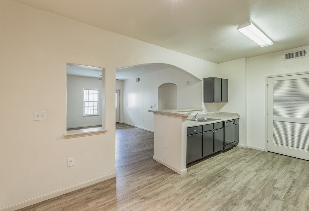an empty kitchen and living room with hardwood flooring and a window