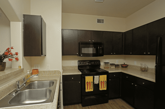 a kitchen with black cabinets and a stove and a sink
