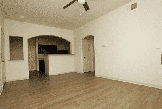an empty living room with a wood floor and a ceiling fan