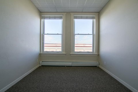 an empty room with three windows and a carpet
