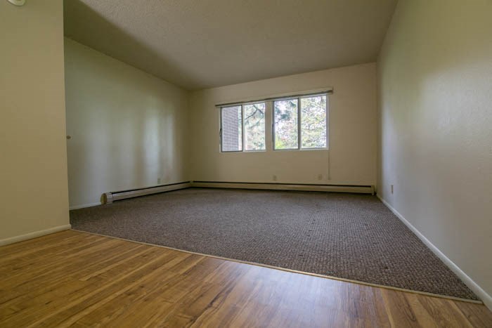 an empty living room with a wooden floor and a window