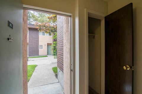 an open door with a view of a yard and a building