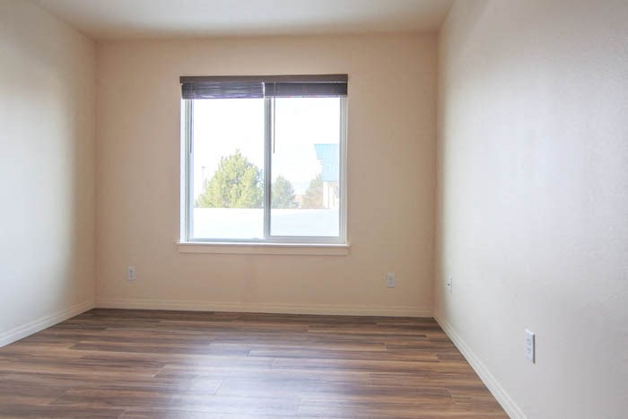 an empty room with a window and wooden floors