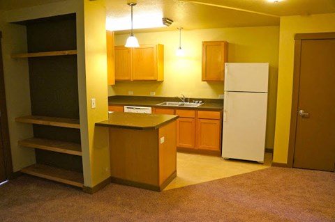 an empty kitchen with a white refrigerator and cabinets