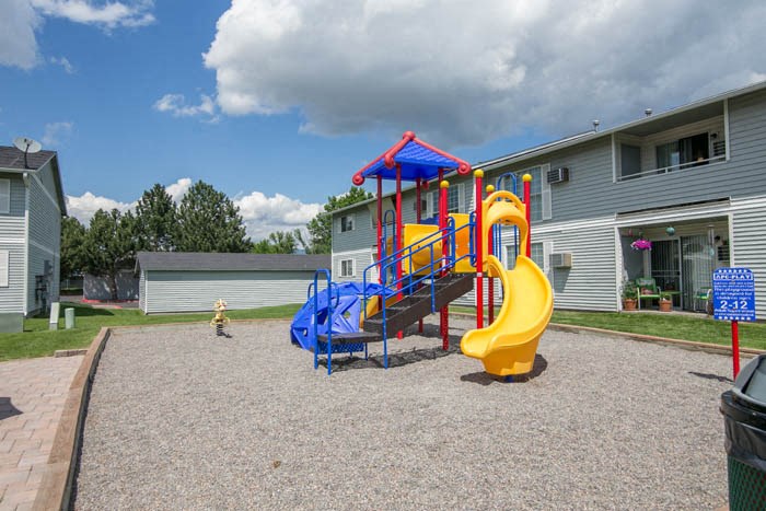 a playground in a yard with a blue and yellow swing set