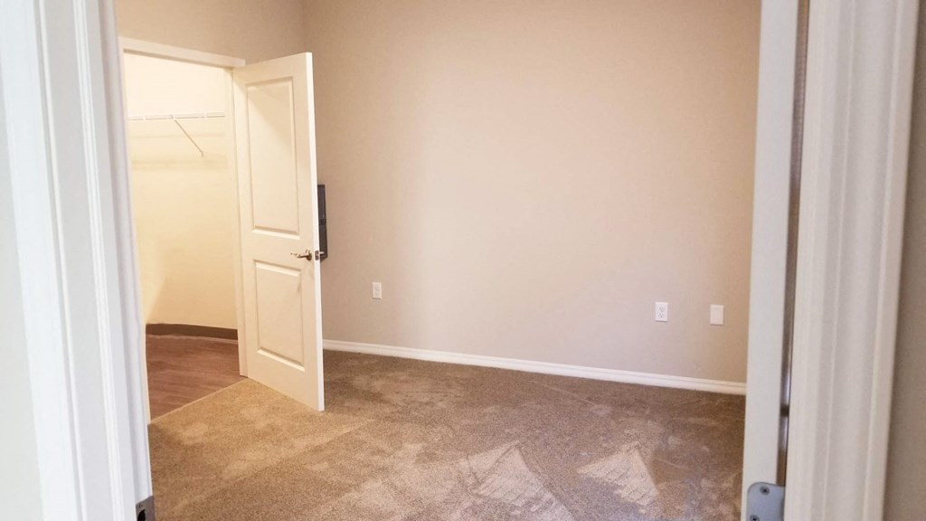 an empty room with a door open to a closet