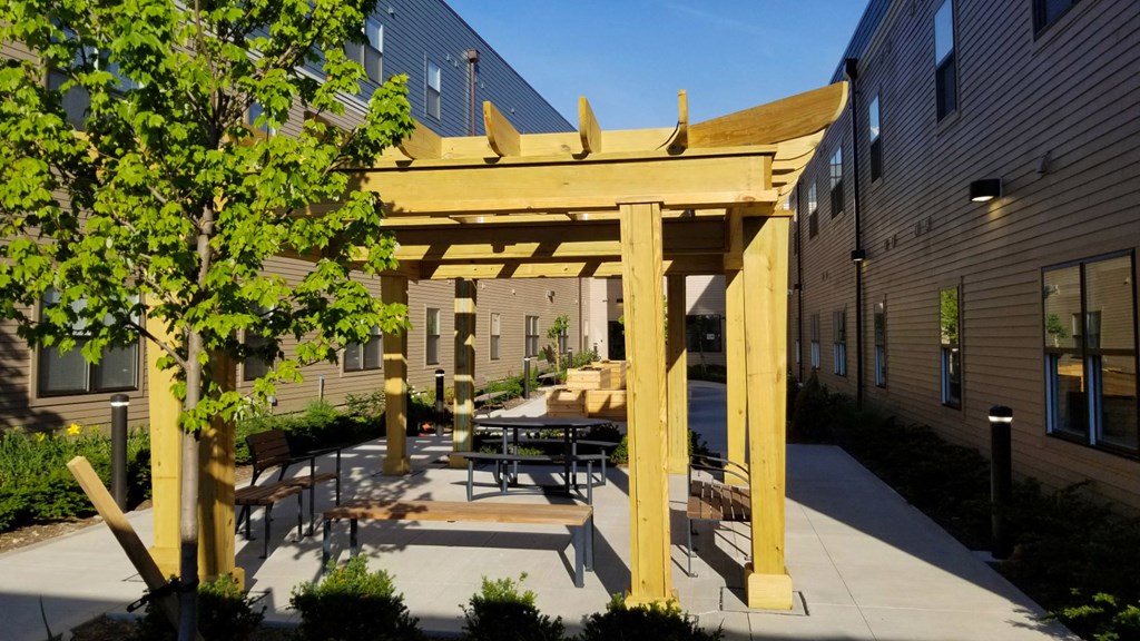 a patio with a table and chairs under a wooden structure