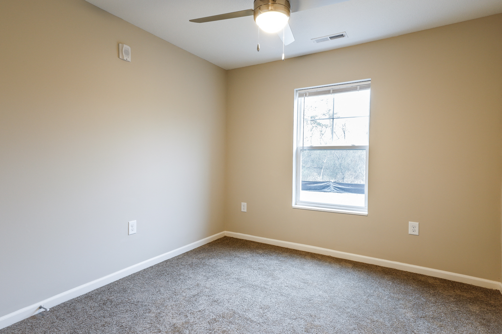 an empty room with a window and a ceiling fan
