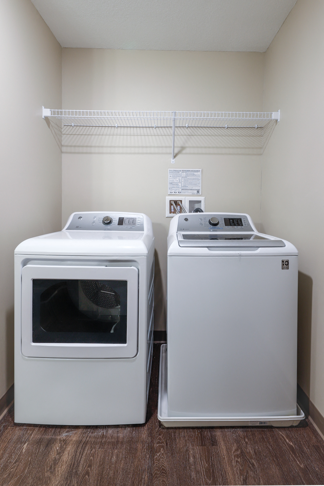 two washers and a dryer in a room with a shelf and a refrigerator