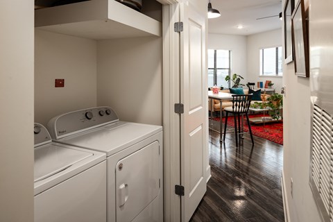 a washer and dryer in a laundry room with a kitchen in the background
