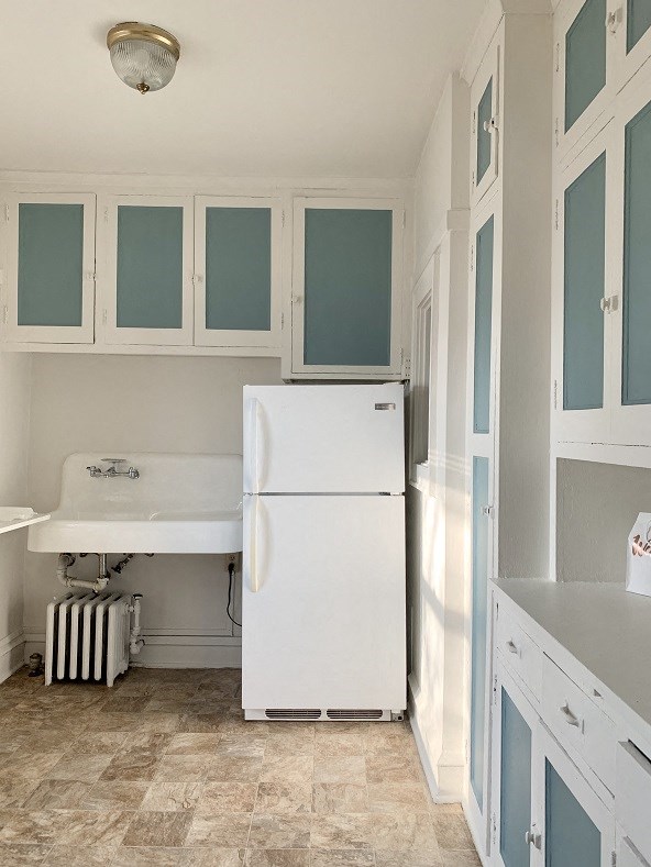 a white kitchen with a refrigerator and a sink
